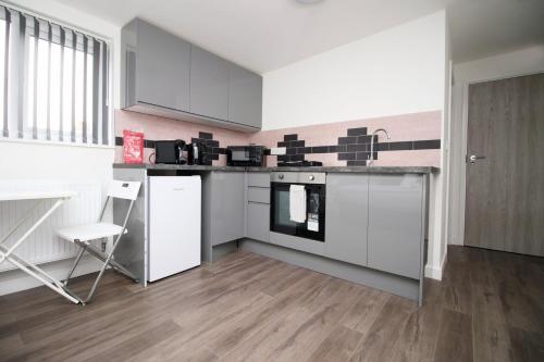 a kitchen with white cabinets and a counter top at Cohost Partners | Smart TV | 5 Min City | Parking in Cardiff