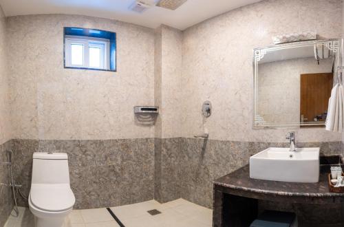 a bathroom with a toilet and a sink and a mirror at Pokhara Alpine and Springs in Pokhara