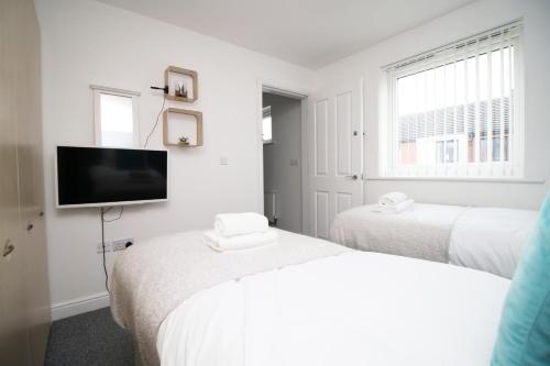 Habitación blanca con 2 camas y TV de pantalla plana. en 4BR modern house Free Parking Cohost Partners, en Newport