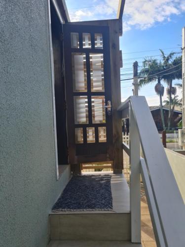 uma porta aberta para uma casa com um corrimão branco em Aluguel de quarto em Torres
