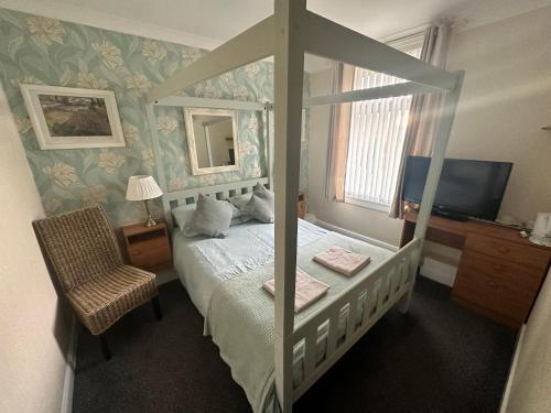 1 dormitorio con cama con dosel y TV en Greenmount Guest House - Pet Friendly - Central to Everything - Everyone Welcome en Blackpool