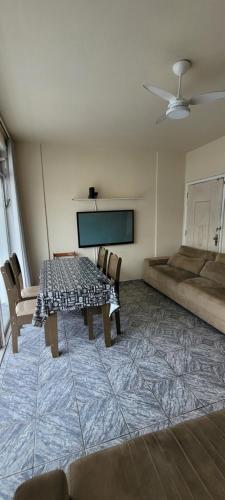 een kamer met een tafel en stoelen en een flatscreen-tv bij Apto Praia Gonzaga - melhor localização in Santos
