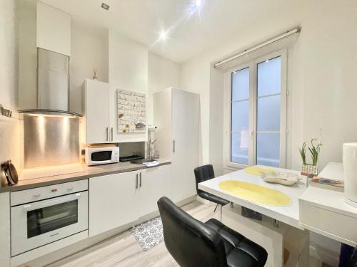 a white kitchen with a table and a microwave at Casa Valfa à 200m du Palais, by Welcome to Cannes in Cannes