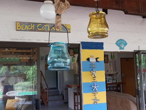 un frasco de cristal colgando del techo con dos luces en Beach Cottage - Hole in the Wall Resort, en Hole in the Wall