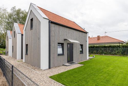 a gray and white house with a grass yard at Solo na wyspie, blisko morza Sobieszewo in Gdańsk