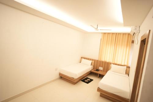Habitación pequeña con 2 camas y ventana en Hotel Shanti International en Deoghar