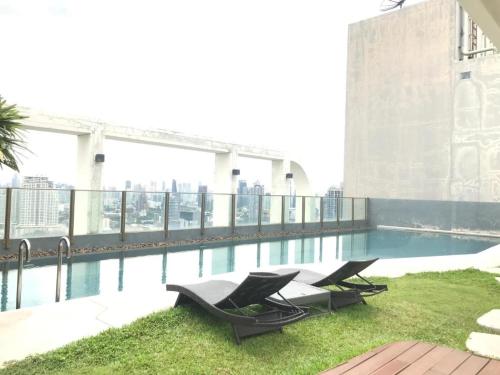 una piscina sul tetto di un edificio con due sedie a sdraio di Sukhumvit 48 BTS Phra khanong 1 Bedroom Apartment, Gym, Swimming pool a Bangkok