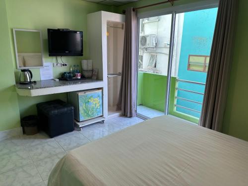 a bedroom with a bed and a tv and a window at Baan Keang Talay Cha Am in Cha Am