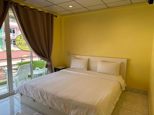 a bedroom with a bed with a yellow wall at Baan Keang Talay Cha Am in Cha Am
