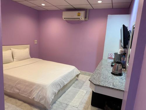 a purple room with a bed and a television at Baan Keang Talay Cha Am in Cha Am
