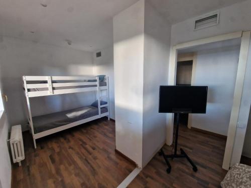 a room with a bunk bed and a desk with a television at Villa Maresme & Villa Rosa in Mataró