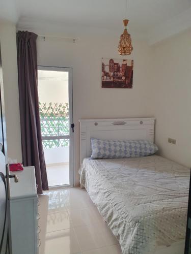 Schlafzimmer mit einem Bett und einer Glasschiebetür in der Unterkunft Apparemment propre in Tangier