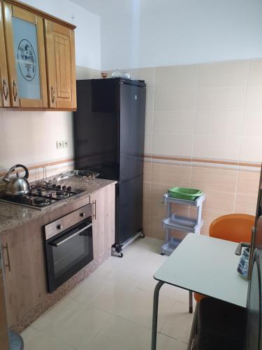 a kitchen with a stove and a black refrigerator at Apparemment propre in Tangier