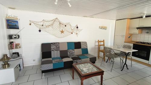 Il dispose d'une cuisine et d'un salon avec un canapé et une table. dans l'établissement La petite maison bleue 2 à 3 personnes, à Andernos-les-Bains