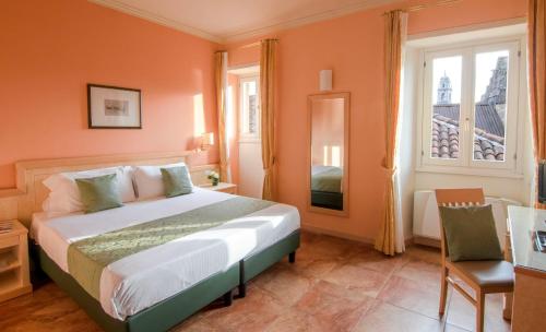 a bedroom with a bed and a window and a mirror at Hotel Belvedere San Gottardo in Verbania