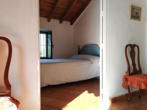 ein kleines Schlafzimmer mit einem Bett und einem Stuhl in der Unterkunft Casa Rural en Montellano (53km de Sevilla) in Montellano