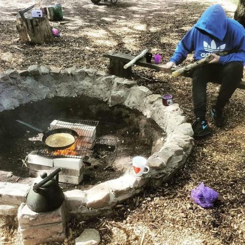 a person is sitting next to a fire pit at Camp Hillcrest, flat, in Gloucestershire