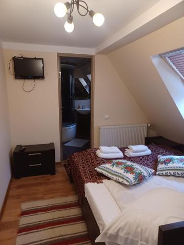a bedroom with two beds and a tv on the wall at Pensiunea IULIA in Rod
