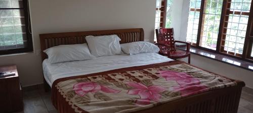 a bedroom with a bed with a flower blanket on it at Waterfront Family Homestay ( Jameela Manzil). in Murinjupuzha