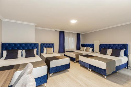 Sirkeci Grand Family Hotel & SPA في إسطنبول: غرفة بثلاث اسرة ذات مقاعد زرقاء