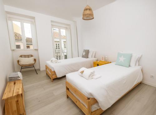 a bedroom with two beds and a chair at Clover House Tavira in Tavira