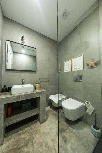 a bathroom with a sink and a toilet and a mirror at Clover House Tavira in Tavira