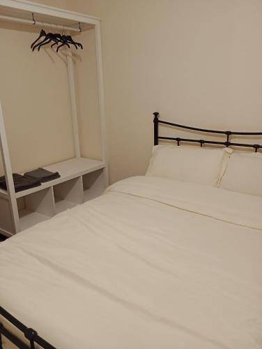 a bedroom with a white bed with a black headboard at Milton Keynes lettings in Milton Keynes