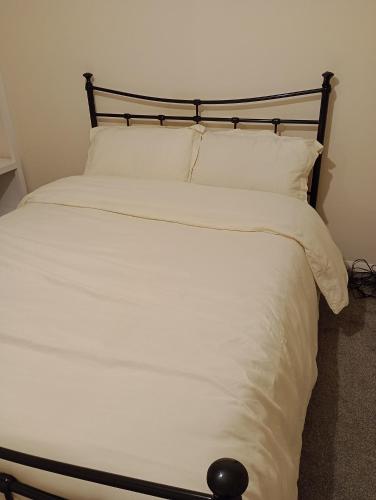 a white bed with white sheets and pillows at Milton Keynes lettings in Milton Keynes