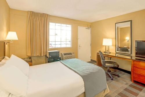 une chambre d'hôtel avec un lit, un bureau et une télévision dans l'établissement Travelodge by Wyndham Silver Spring, à Silver Spring