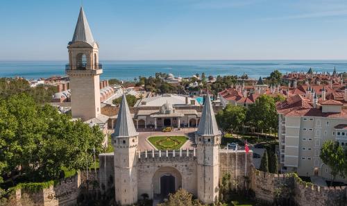 a castle with a clock tower and a city at Swandor Hotels & Resorts - Topkapi Palace in Lara