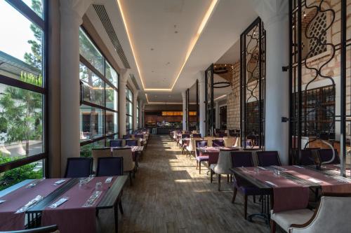 a restaurant with tables and chairs and windows at Swandor Hotels & Resorts - Topkapi Palace in Lara
