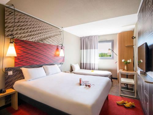 um quarto de hotel com uma cama grande e uma televisão em ibis Bordeaux Centre Bastide em Bordéus