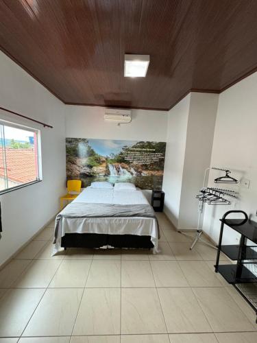 a bedroom with a bed and a painting on the wall at Pousada Caminho das Cachoeiras Pirenopolis in Pirenópolis