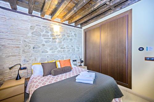 1 dormitorio con cama y pared de piedra en El Patio de Toledo, en Toledo