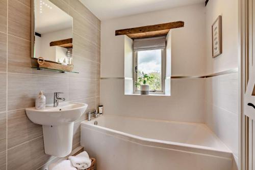 a white bathroom with a sink and a tub and a mirror at Perry Cottage in Halford