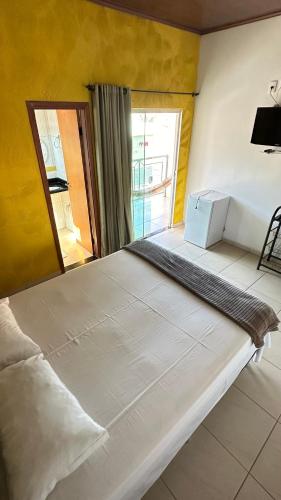 a large white bed in a room with a mirror at Pousada Caminho das Cachoeiras Pirenopolis in Pirenópolis