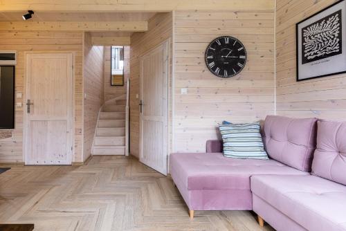 a living room with a purple couch and a clock at Solo na wyspie, blisko morza Sobieszewo in Gdańsk