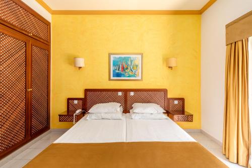 a bedroom with a large bed with yellow walls at Hotel Casabela in Ferragudo