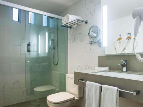 een badkamer met een douche, een toilet en een wastafel bij Novotel Rio de Janeiro Leme in Rio de Janeiro