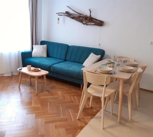 een woonkamer met een blauwe bank en een tafel bij Apartament Szklar-Ski in Szklarska Poręba