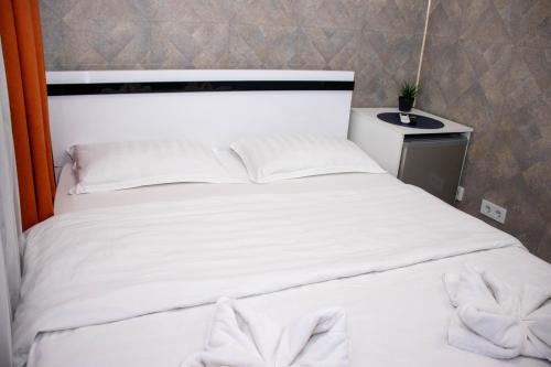 a white bed with white pillows on top of it at AG Hotel in Almaty