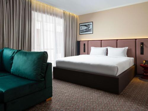 a hotel room with a bed and a couch at Mercure Chisinau Center Jazz Hotel in Chişinău