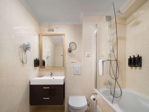 a bathroom with a toilet and a sink and a shower at Mercure Chisinau Center Jazz Hotel in Chişinău