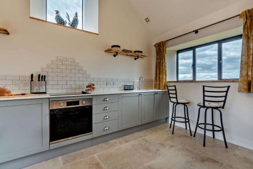 a kitchen with white cabinets and two bar stools at Fox in Charlbury