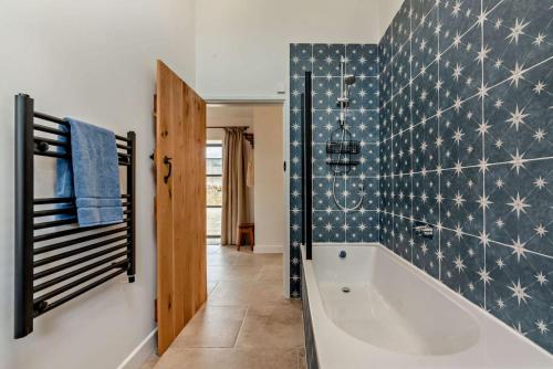 a bathroom with a tub and a tile wall at Fox in Charlbury