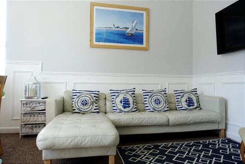 a living room with a white couch with blue and white pillows at The Captain's Lodge Looe in Looe