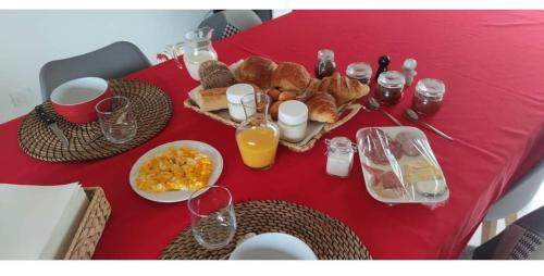 uma mesa vermelha coberta com alimentos para o pequeno-almoço e sumo de laranja em Chambre d hôte Beaumont pied de bœuf em Beaumont-Pied-de-Boeuf