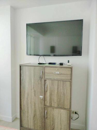 um armário de madeira com uma televisão de ecrã plano na parede em Oasis at Azure Urban Resorts em Manila