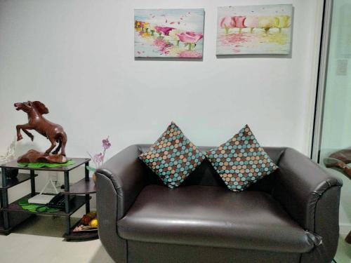 um sofá de couro com almofadas na sala de estar em Oasis at Azure Urban Resorts em Manila