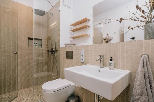 a bathroom with a sink and a toilet and a shower at TheChipp - Designapartment mit Seeblick, Pool, Sauna & Kamin in Bad Saarow